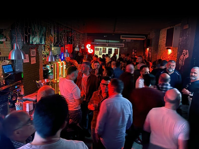 Packed bar room with red neon at Bacon Bear Bar