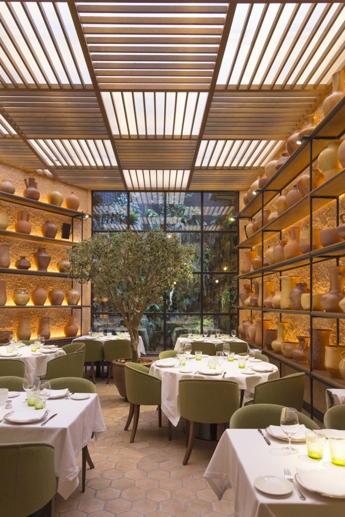 Glass atrium at L'Olivé with an olive tree and terracotta jars