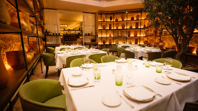 Main dining room at L'Olivé with white tablecloths and green velvet chairs