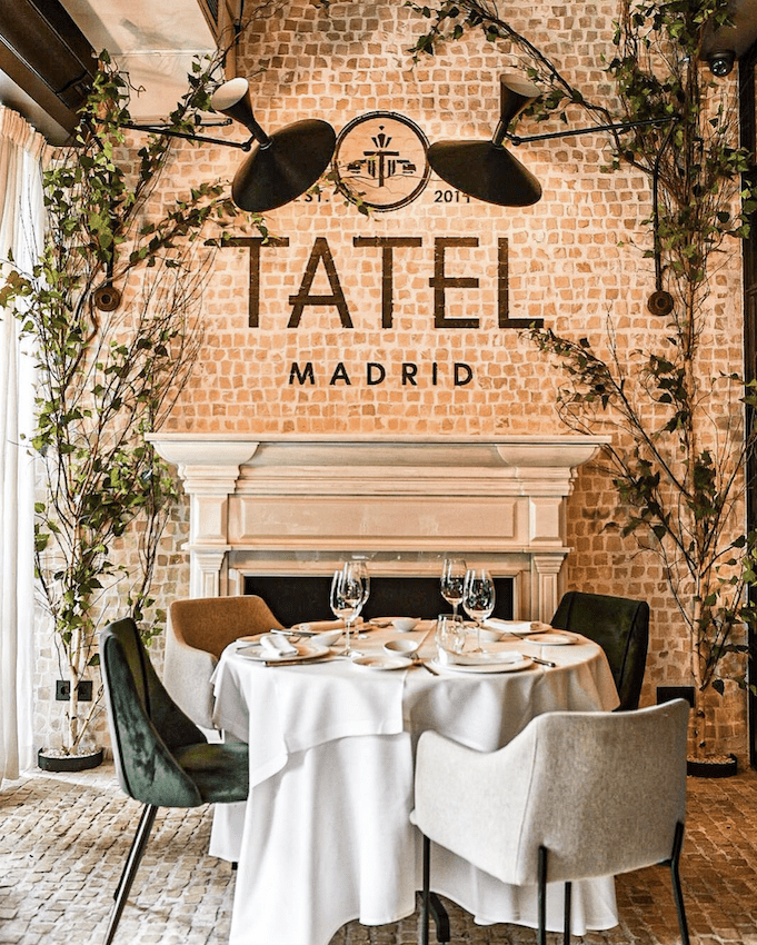 Fireplace table at TATEL Madrid with the logo on exposed brick